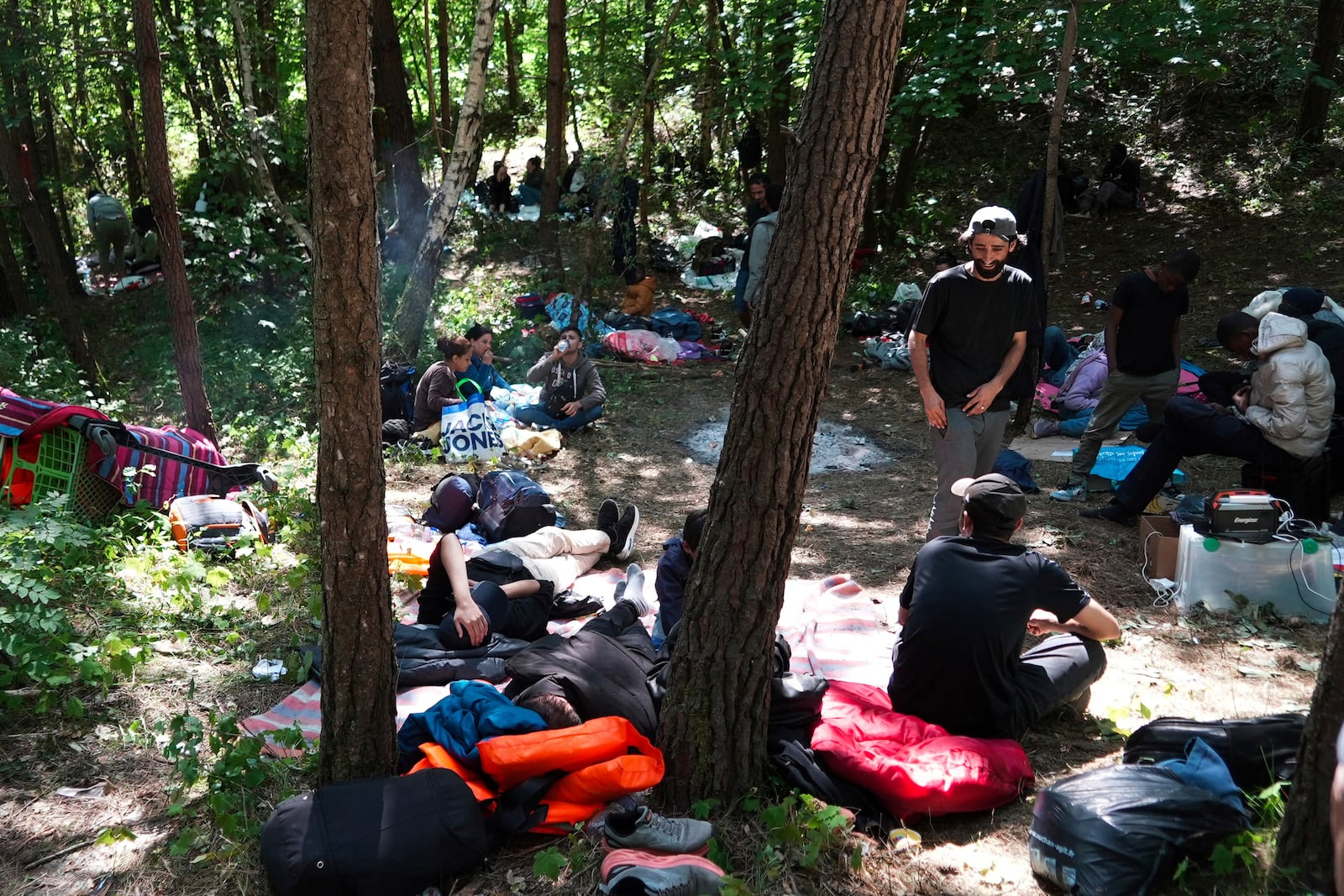 Migrants wait in the Ecault forest, northern France, Thursday, July 3, 2025. (AP Photo/Nicolas Garriga)