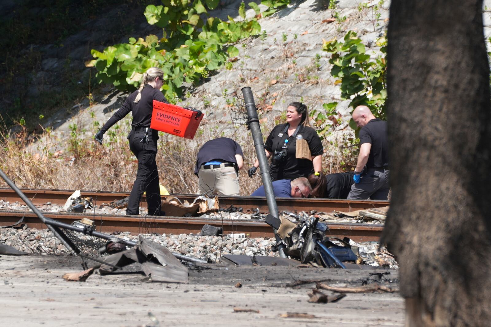 Emergency personnel remove the bodies of those killed when a small plane crashed on the railroad tracks beneath the overpass near Interstate 95 in Boca Raton, Fla., on Friday, April 11, 2025. (AP Photo/Marta Lavandier)