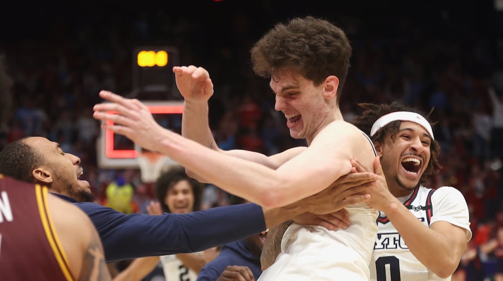 Dayton's Javon Bennett, right, and Zed Key, left, celebrate with Amaël L'Etang after his game-winning basket in overtime against Loyola Chicago on Saturday, Jan. 18, 2025, at UD Arena. David Jablonski/Staf