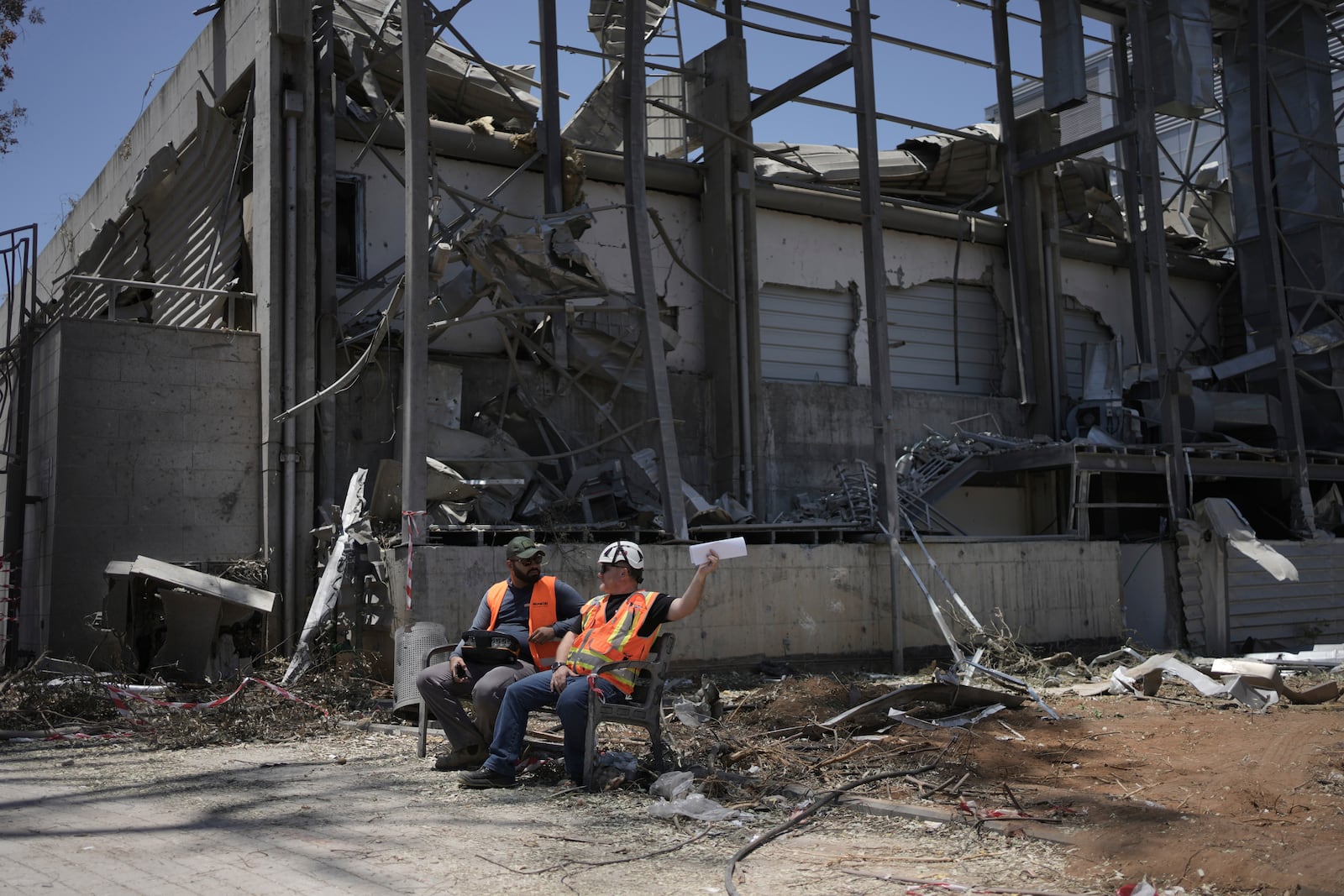 Workers sit next to a building at the Weizmann Institute of Science destroyed by an Iranian missile in Rehovot, Thursday, June 19, 2025. (AP Photo/Maya Alleruzzo)
