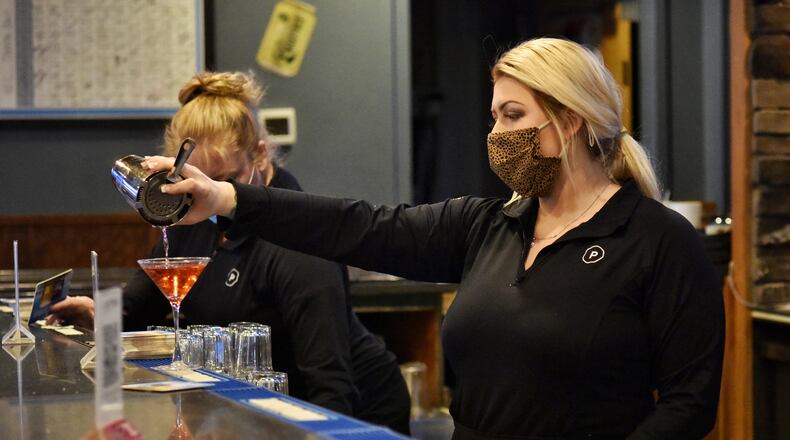 Hayley Moser makes a cosmopolitan for a customer at Putters Sports Grill on Cincinnati Dayton Road Thursday, February 11, 2021 in Liberty Township. NICK GRAHAM / STAFF
