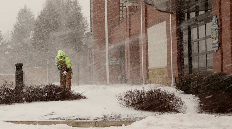 An Englewood Service Department employee shovels the sidewalk in front of the government center Thursday as heavy snow starts to fall.