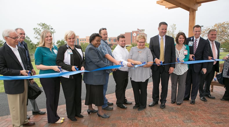 Atrium Medical Center executives celebrate the completion of a paved walking trail surrounding the hospital. The path loops through gardens surrounding the hospital in Middletown. WAYNE BAKER/STAFF