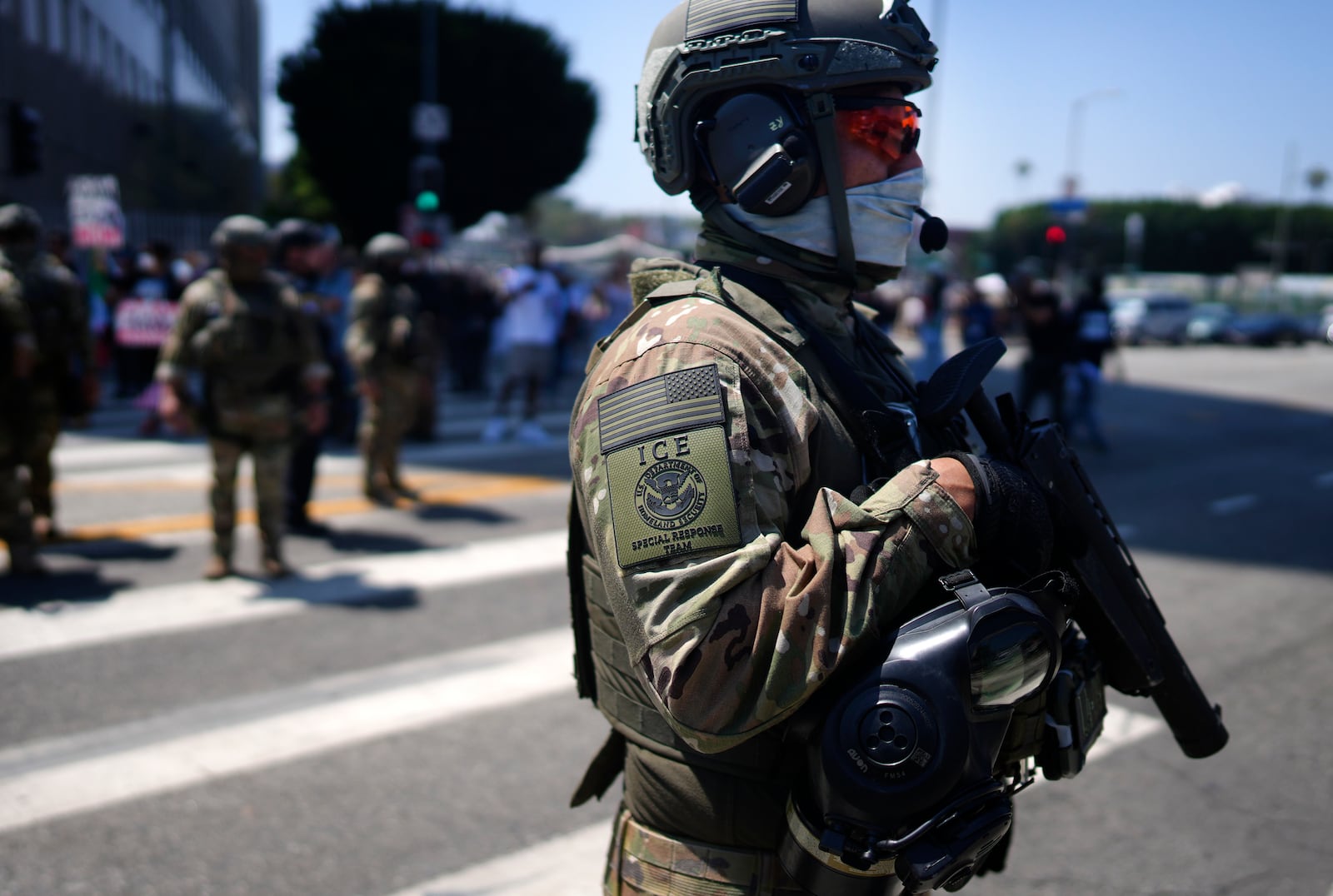 An ICE Special Response Team member stands guard outside the Metropolitan Detention Center, while protesters gather outside to denounce the ICE, U.S. Immigration and Customs Enforcement, operations, Tuesday, June 10, 2025, in downtown Los Angeles. (AP Photo/Eric Thayer)