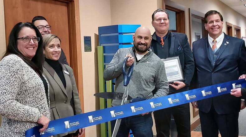 Artist Nick Bauer cut the ribbon of the sculpture he created that sits in the lobby of the West Chester/Liberty Chamber Alliance. Photo: Sue Kiesewetter/Journal-News