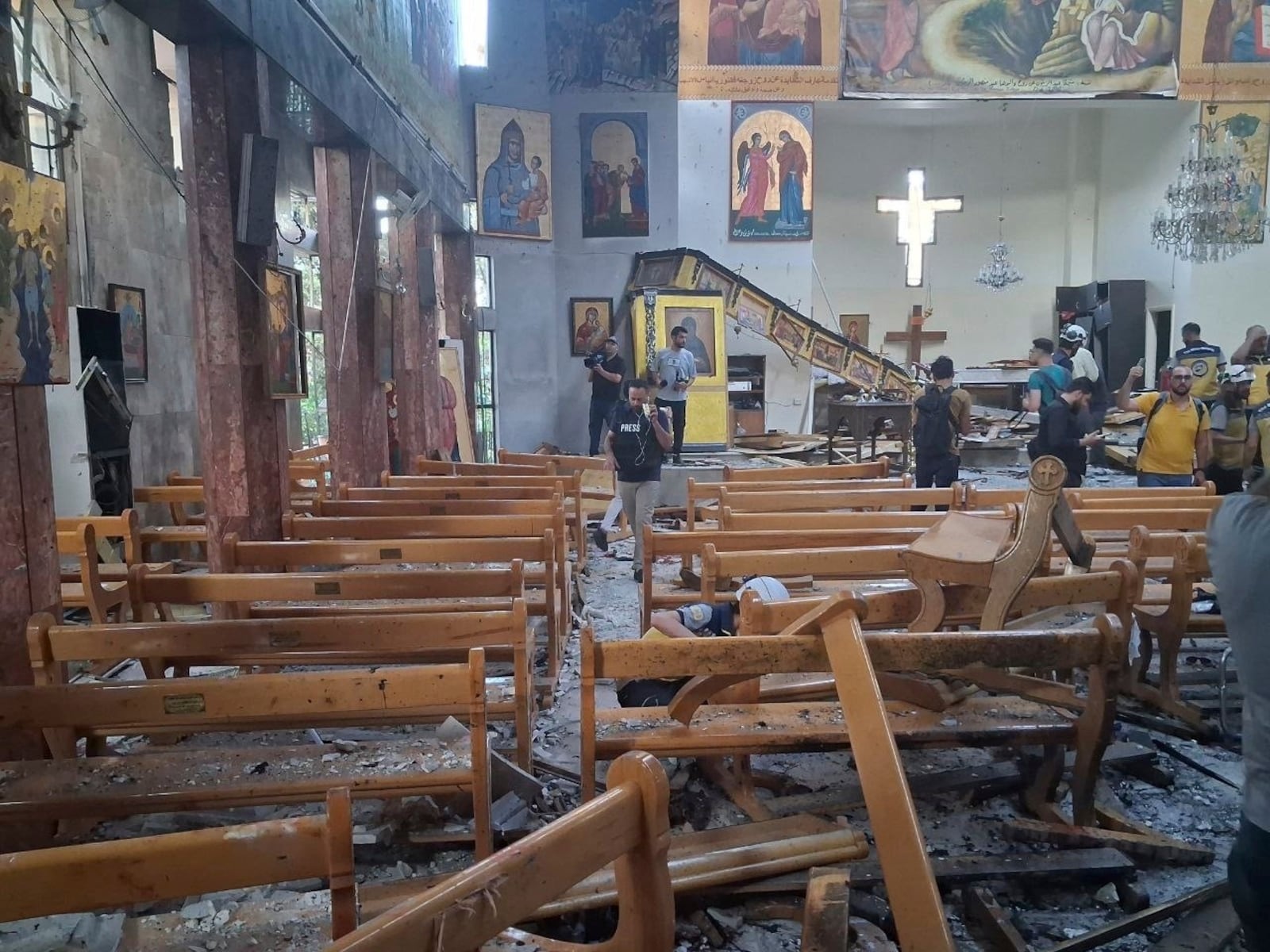 In this photo released by the Syrian official news agency SANA, journalists and Civil Defence workers inspect the damage inside Mar Elias church where a suicide bomber detonated himself in Dweil'a in the outskirts of Damascus, Syria, Sunday June 22, 2025. (SANA via AP)