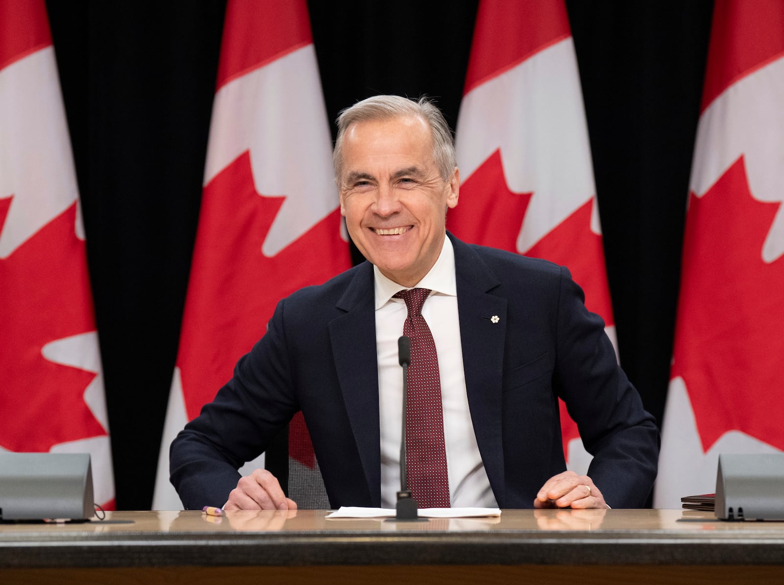 Prime Minister Mark Carney smiles as he takes his seat at his first news conference since winning the federal election, in Ottawa, Friday, May 2, 2025. (Adrian Wyld /The Canadian Press via AP)