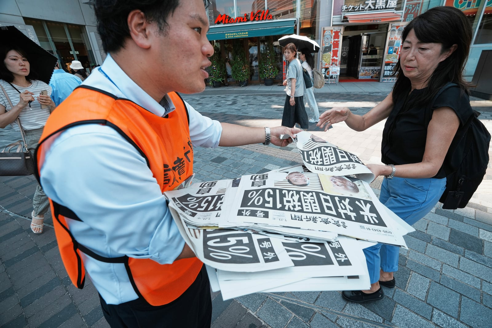 A staff member distributes an extra edition of the Yomiuri Shimbun newspaper reporting that President Donald Trump announced a trade framework with Japan on Tuesday, Wednesday, July 23, 2025, in Tokyo. (AP Photo/Eugene Hoshiko)