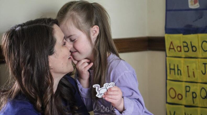 Jenny Lake teaches her daughter, Olivia Livy Lake at their home in the Bellbrook School district.Olivia, a kindergartner with Down syndrome, normally gets special education services from several professionals in Bellbrook-Sugarcreek schools. Now Jenny Lake is shouldering much of that burden, while communicating with the teachers and therapists. (Photo By JIM NOELKER/Dayton Daily News)