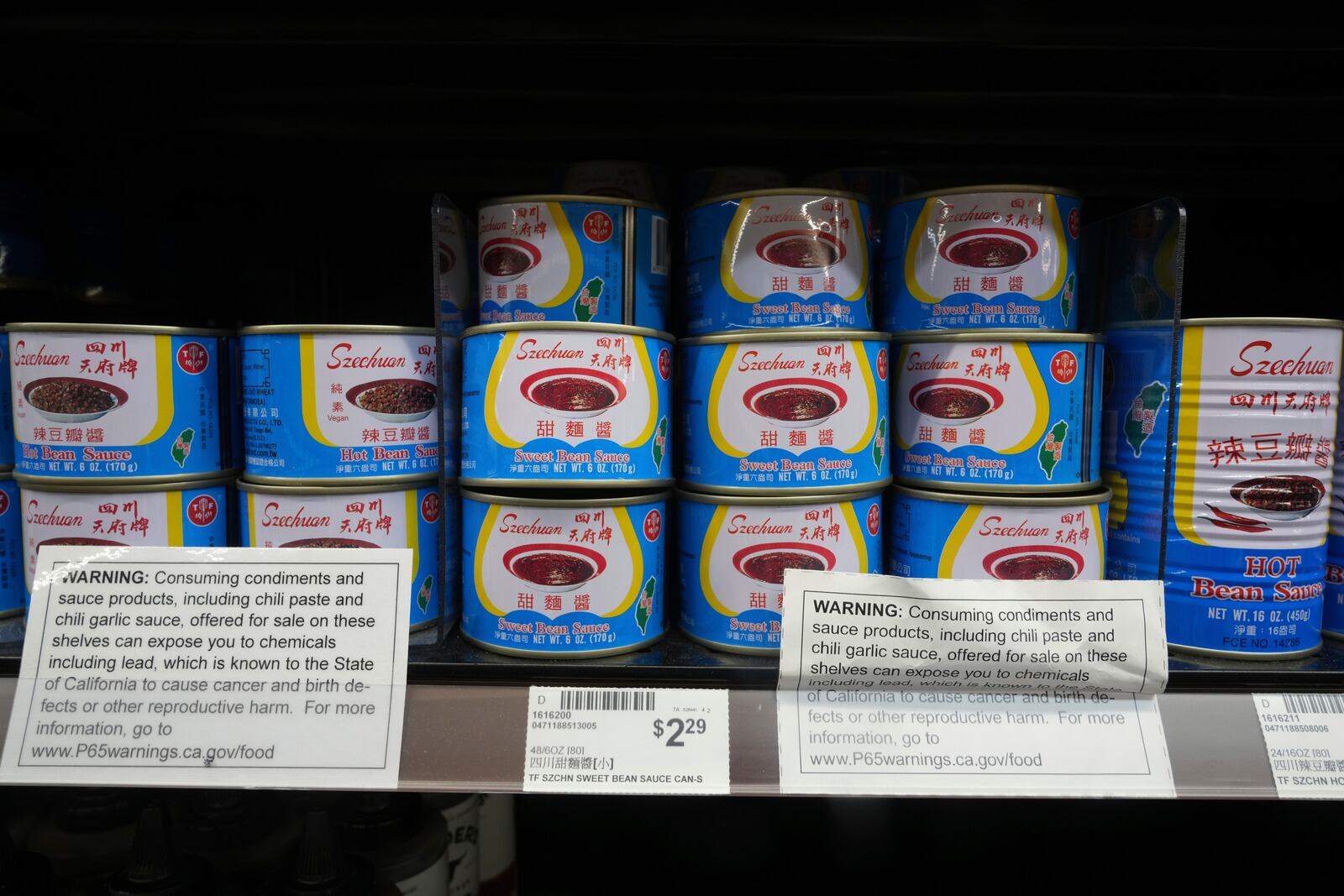 Cans of Szechuan sweet ban sauce sit with a California Proposition P65 chemicals warning label in an aisle at 99 Ranch Market, an Asian grocery store in Los Angeles Monday, April 7, 2025. (AP Photo/Damian Dovarganes)