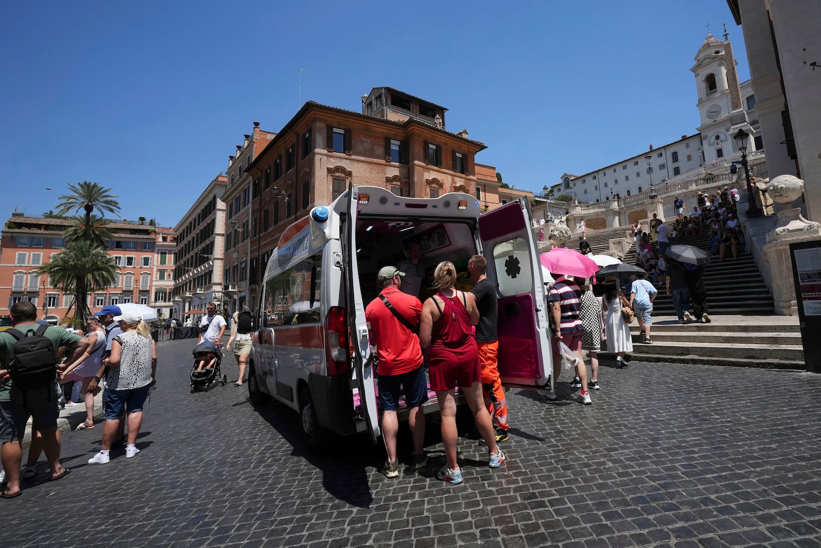 FILE - Paramedics provide aid to tourists and residents with an ambulance, next to the historical Spanish Steps, in Rome, Italy, July 1, 2025. (AP Photo/Andrew Medichini)