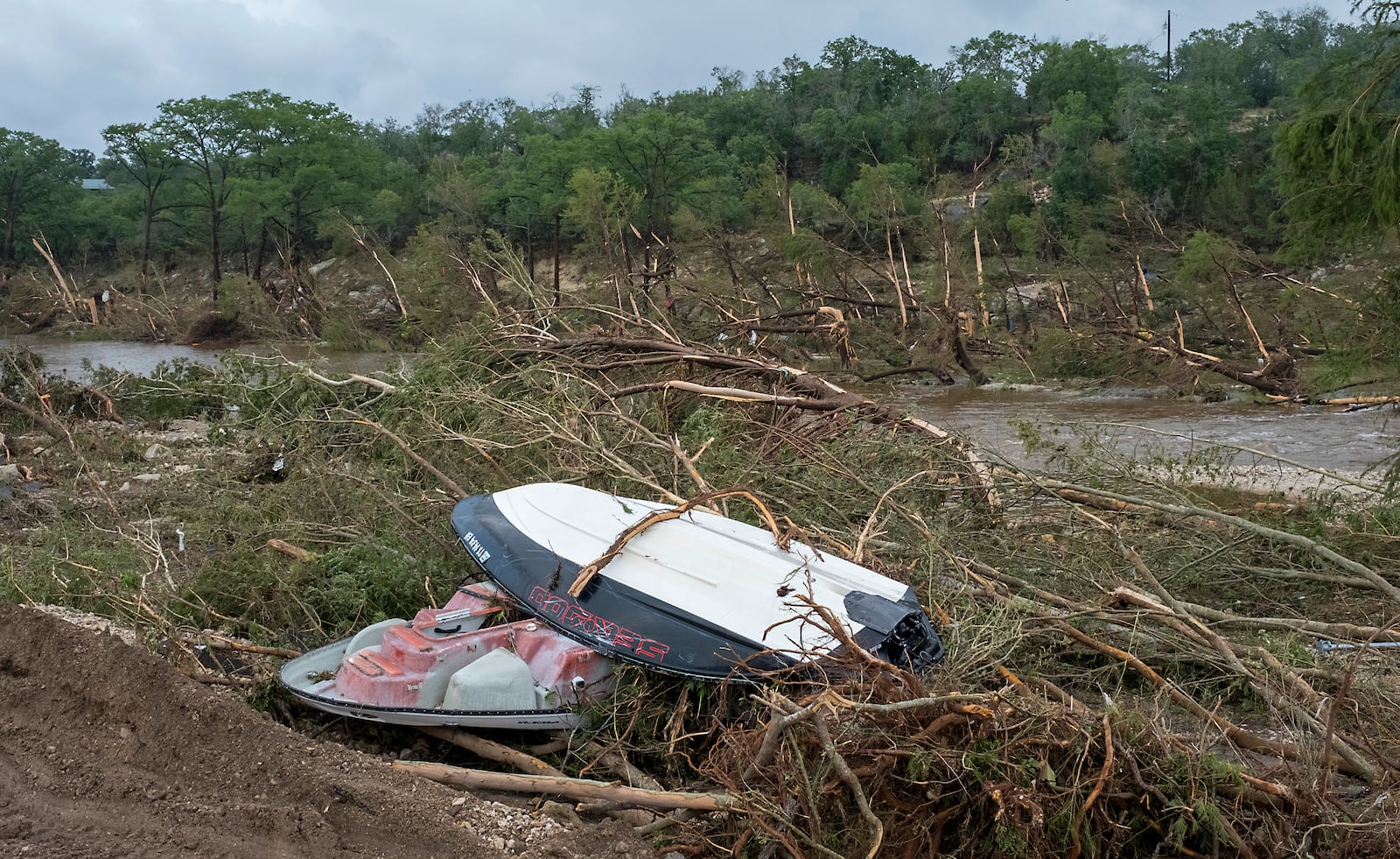 Damaged boats and debris litter the banks of the Guadalupe River near Cade Loop on Saturday, July 5, 2025, in Ingram, Texas. (AP Photo/Rodolfo Gonzalez)