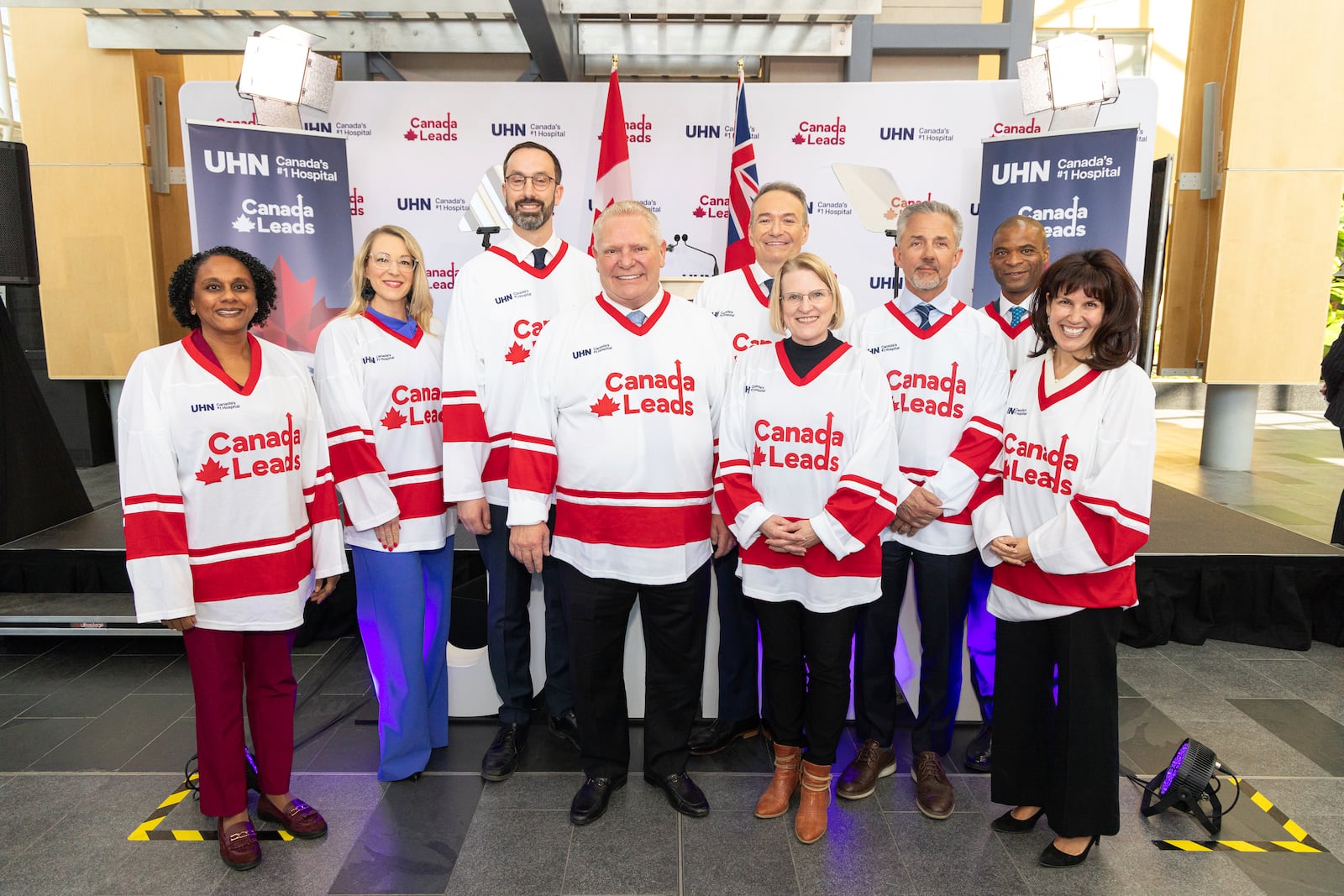 In this photo provided by the University Health Network, Ontario Premier Doug Ford, center, stands with other government and UHN officials in custom hockey jerseys during the announcement of the "Canada Leads" program in Toronto on Monday, April 7, 2025. (Jacob Cote/UHN via AP)