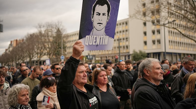 A man hold placard of the killed student as he takes part in a march in Lyon, France, Saturday, Feb. 21, 2026, to pay tribute to Quentin Deranque, a 23-year-old nationalist activist who died from a beating after a clash between far-left and far-right supporters. (AP Photo/Laurent Cipriani)