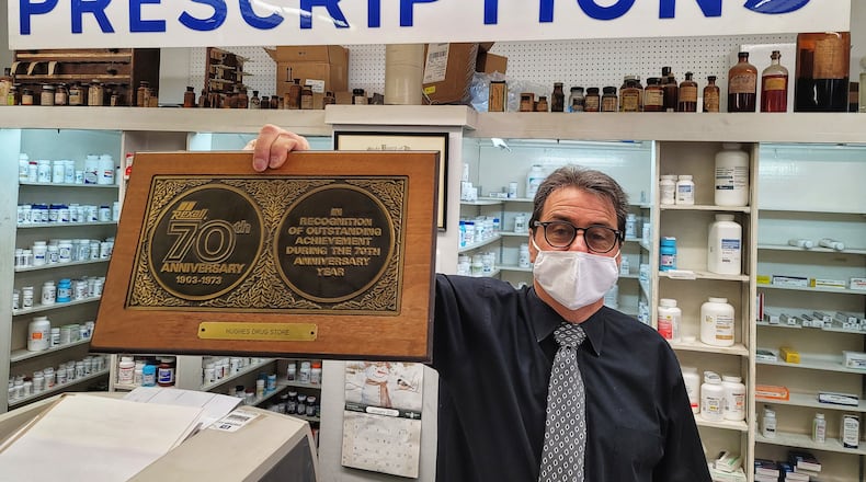 Pharmacist Jim Fescina shows some of the historic items on display in Hughes Pharmacy Wednesday, January 27, 2021. Hughes Pharmacy, a business that has been in Hamilton for over 100 years, will close its doors permanently on Saturday. NICK GRAHAM / STAFF