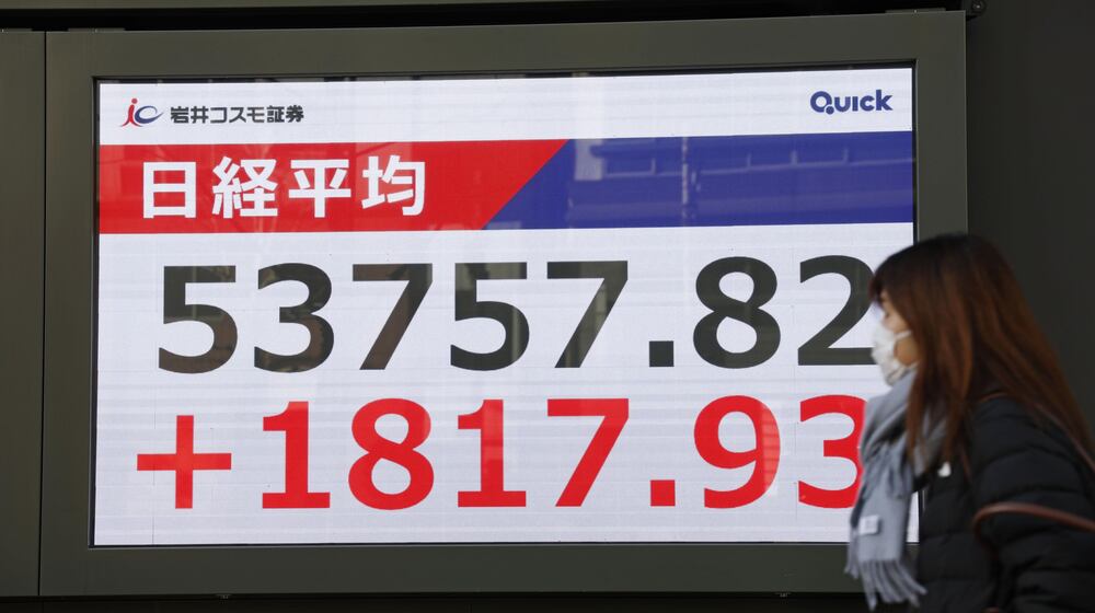 A person walks in front of an electronic stock board showing Japan's Nikkei index at a securities firm Tuesday, Jan. 13, 2026, in Tokyo. (Kyodo News via AP)