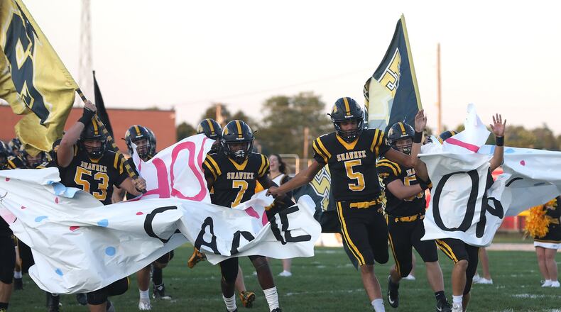 Shawnee’s Robie Glass leads the Braves onto the field before their game against Tecumseh. BILL LACKEY/STAFF