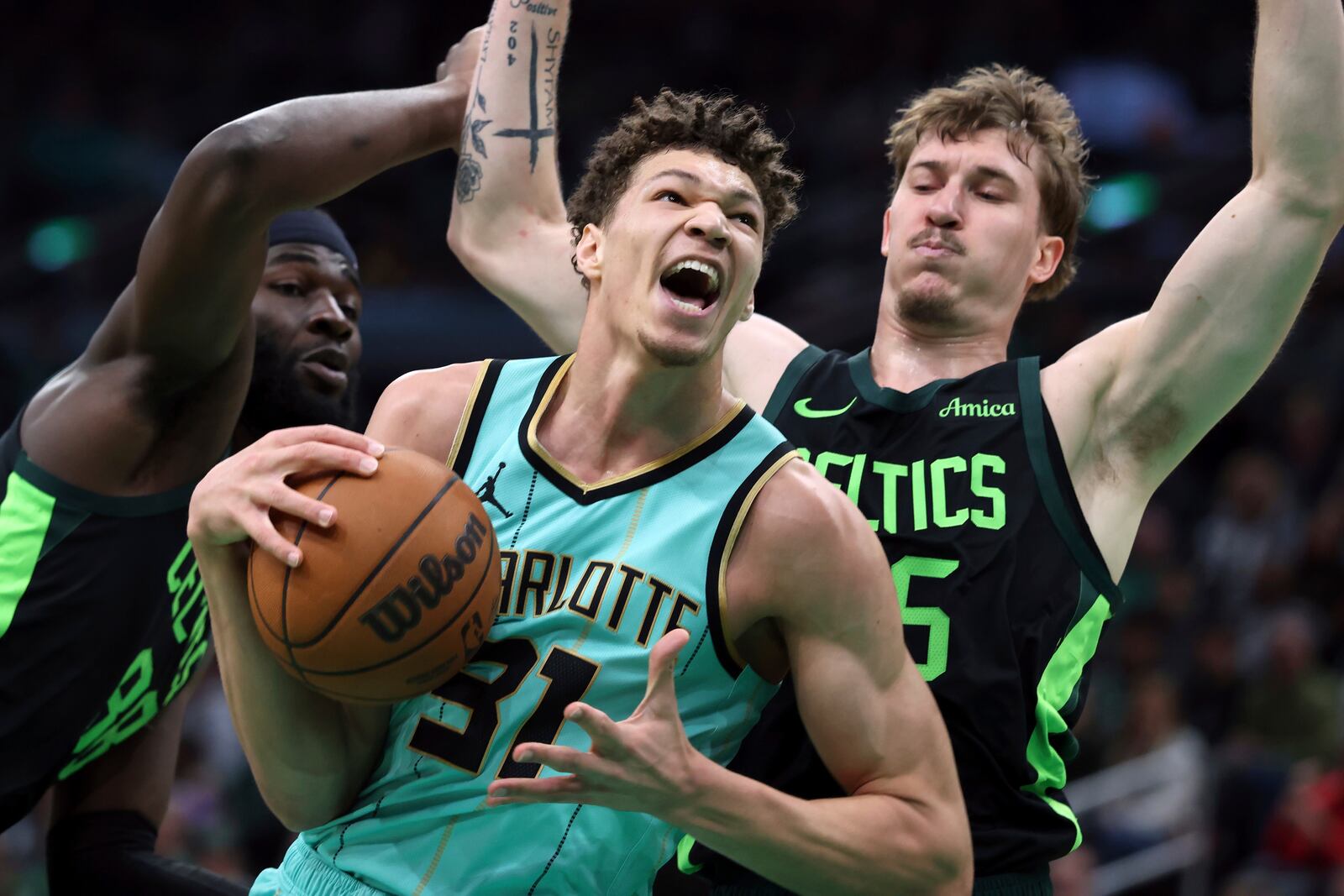 Charlotte Hornets' Tidjane Salaun (31) drives for the basket against Boston Celtics' Neemias Queta (88) and Baylor Scheierman (55) during the first half of an NBA basketball game Sunday, April 13, 2025, in Boston. (AP Photo/Michael Dwyer)
