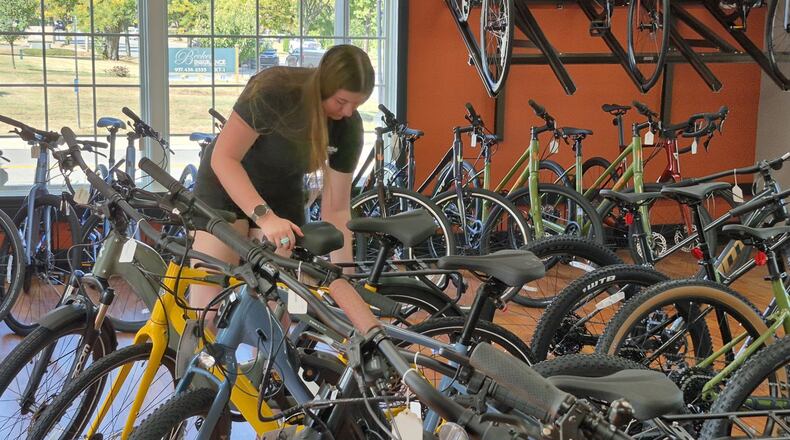 Bike mechanic Greta Waller adjusts displays at K&G Bike Center, 116 W. Franklin St., Centerville. Shop management is hopeful foot traffic translates to strong holiday sales. MICHAEL KURTZ / STAFF