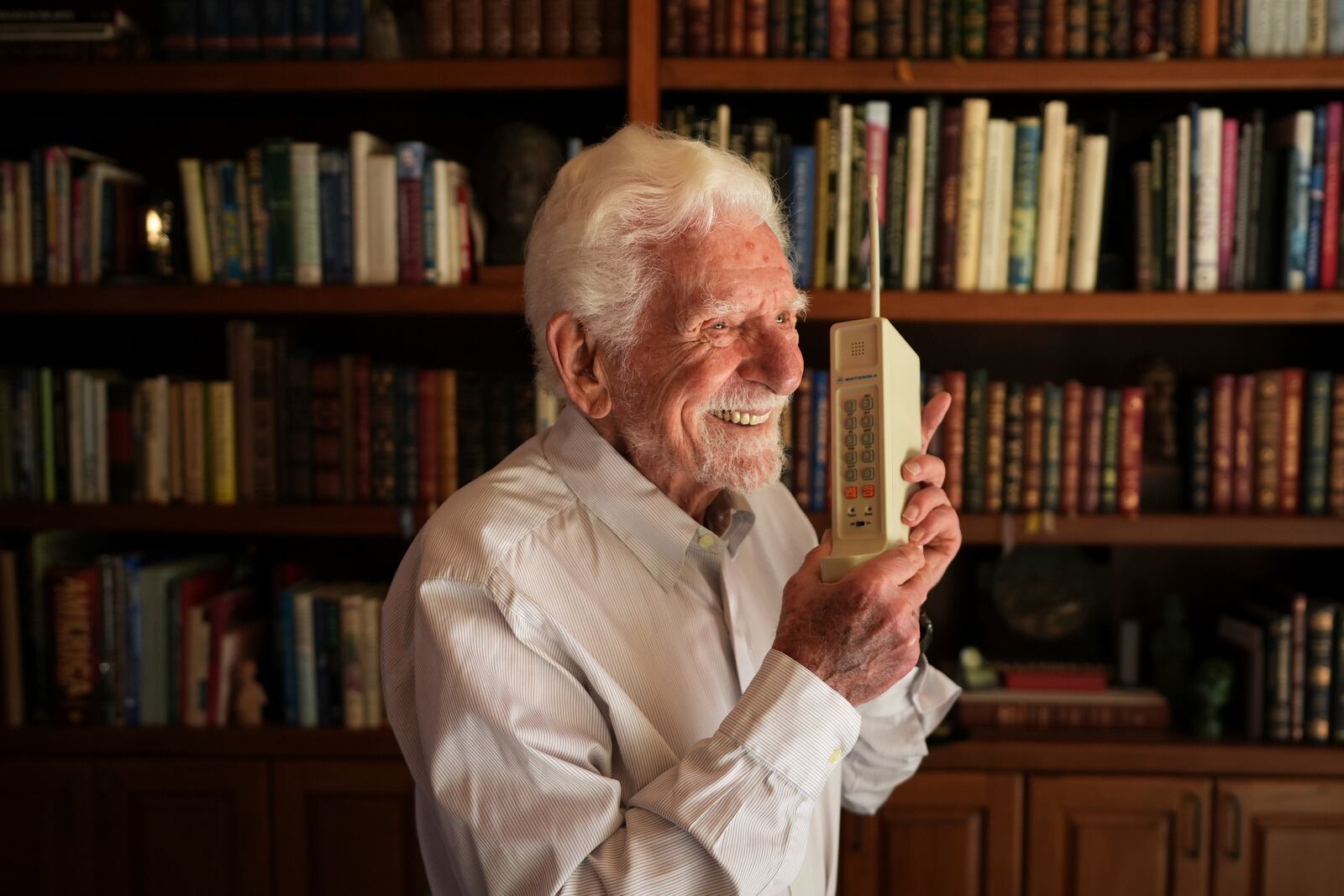 Martin Cooper, who led the team that built the first mobile cellphone, sits behind a prototype of that phone at his home, April 4, 2025, in San Diego. (AP Photo/Gregory Bull)