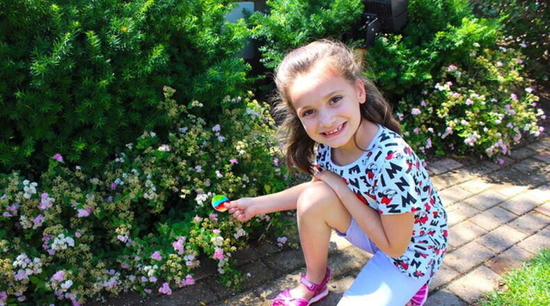 A young geocacher with one of the collectible coins from Haute Fusion Glass Studio that will be periodically placed in the caches. CONTRIBUTED