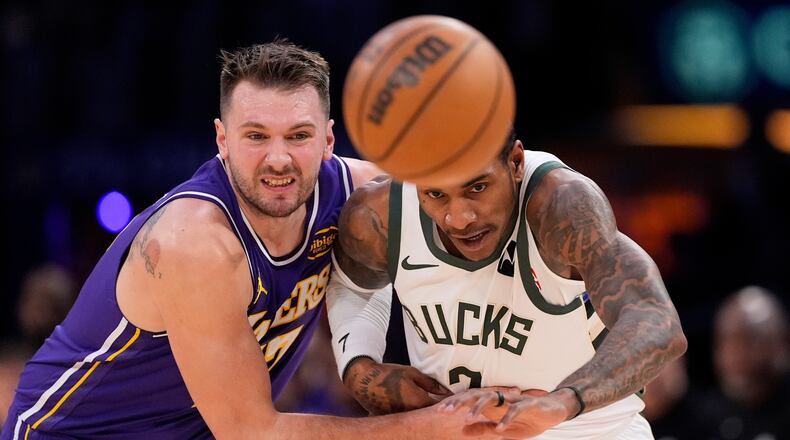 Los Angeles Lakers guard Luka Doncic, left, and Milwaukee Bucks guard Kevin Porter Jr. go after a loose ball during the first half of an NBA basketball game Friday, Jan. 9, 2026, in Los Angeles. (AP Photo/Mark J. Terrill)