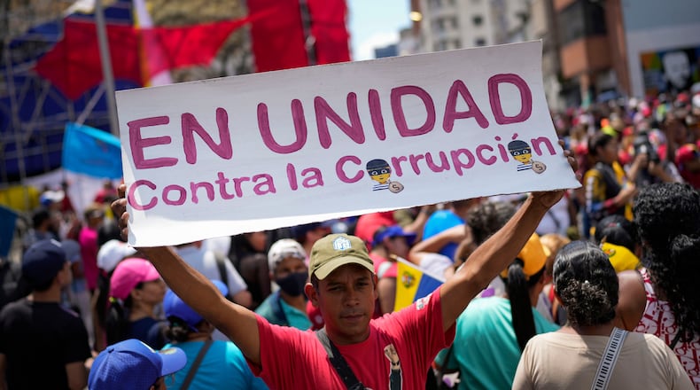 FILE - A government supporter holds a sign with a message that reads in Spanish: "In unity against corruption", during a rally against corruption, in Caracas, Venezuela, Saturday, March 25, 2023. (AP Photo/Matias Delacroix, File)