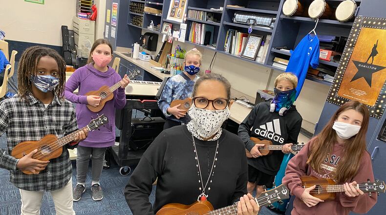 Larissa McIntosh (center), sixth grade choir and strings teacher at Springboro Intermediate School, organized a fundraiser to purchase ukuleles for her choir students to learn and play. CONTRIBUTED PHOTO / SCOTT MARSHALL