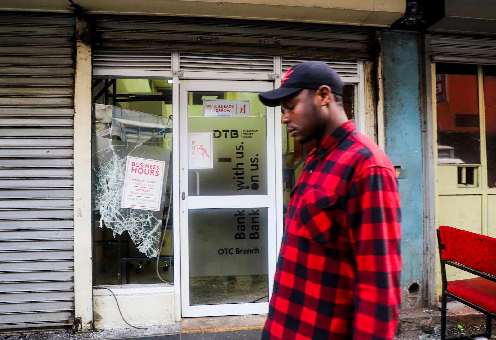 A man walks past a vandalized bank following the one-year anniversary of a deadly anti-tax demonstrations in Nairobi, Kenya, Thursday, June 26, 2025. (AP Photo/Patrick Ngugi)