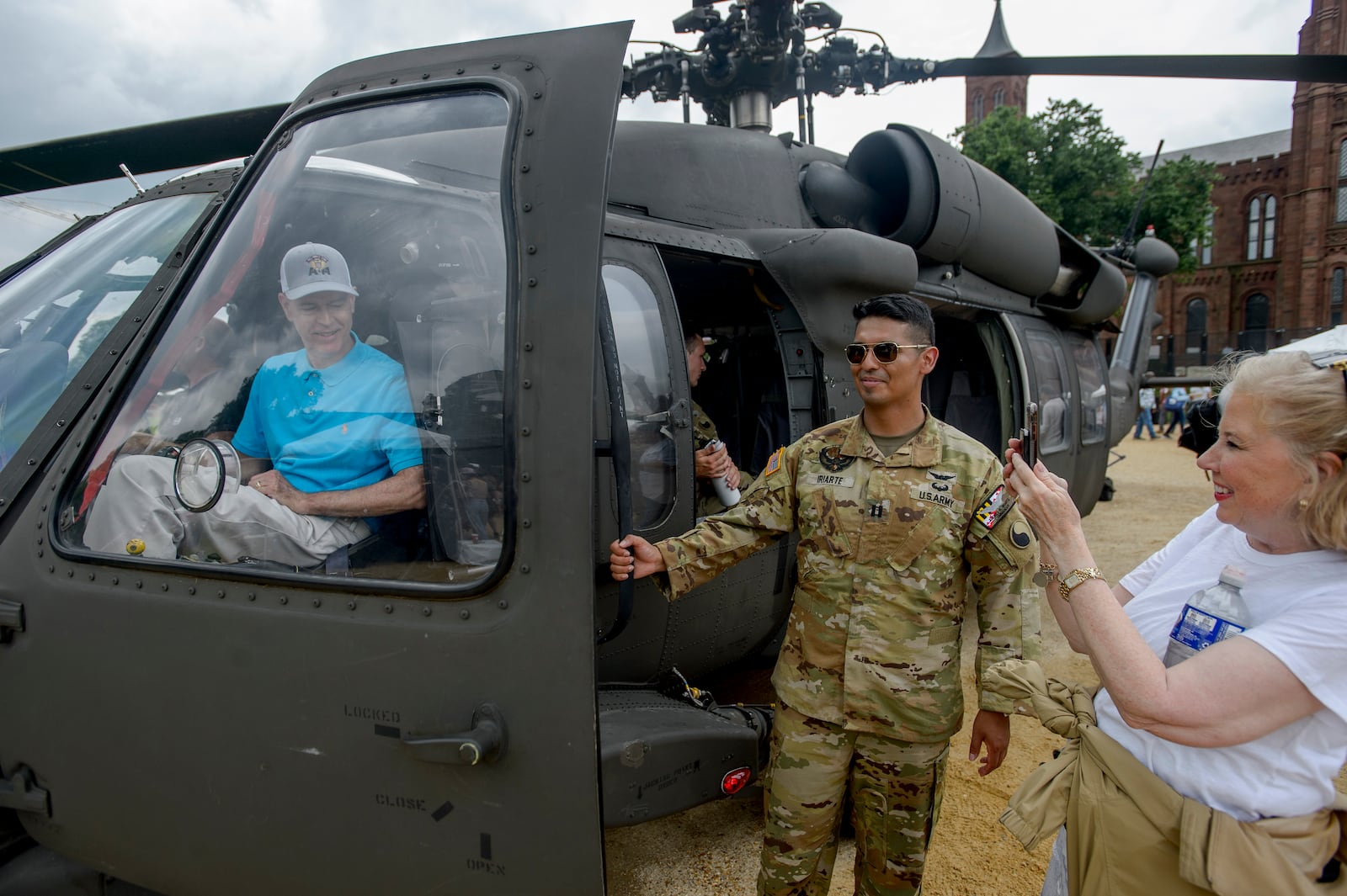 Dale Booth, left, of Tyler, Texas, poses in a Blackhawk helicopter for his wife Jan Booth, right, during the festival event to honor the Army's 250th anniversary, coinciding with President Donald Trump's 79th birthday, Saturday, June 14, 2025, on the National Mall in Washington. (AP Photo/Rod Lamkey, Jr.)