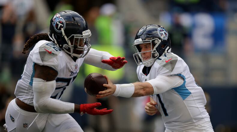 Tennessee Titans quarterback Ryan Tannehill, right, hands off to running back Derrick Henry during the second half of an NFL football game against the Seattle Seahawks, Sunday, Sept. 19, 2021, in Seattle. The Titans won 33-30 in overtime. (AP Photo/John Froschauer)