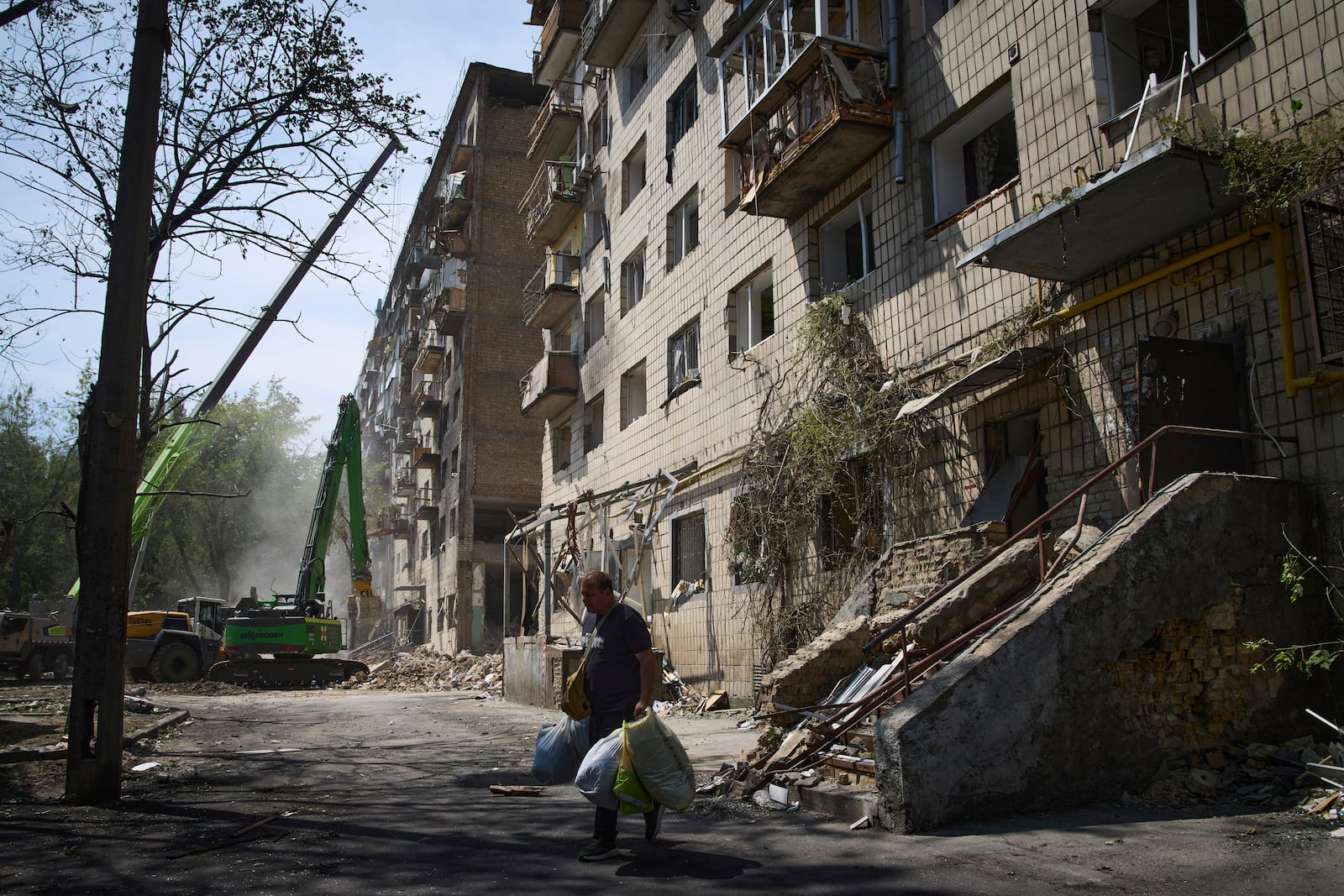An elderly man carries belongings from his apartment that was destroyed by Russia's missile attack on Tuesday, in Kyiv, Ukraine, Wednesday, June 18, 2025.(AP Photo/Efrem Lukatsky)