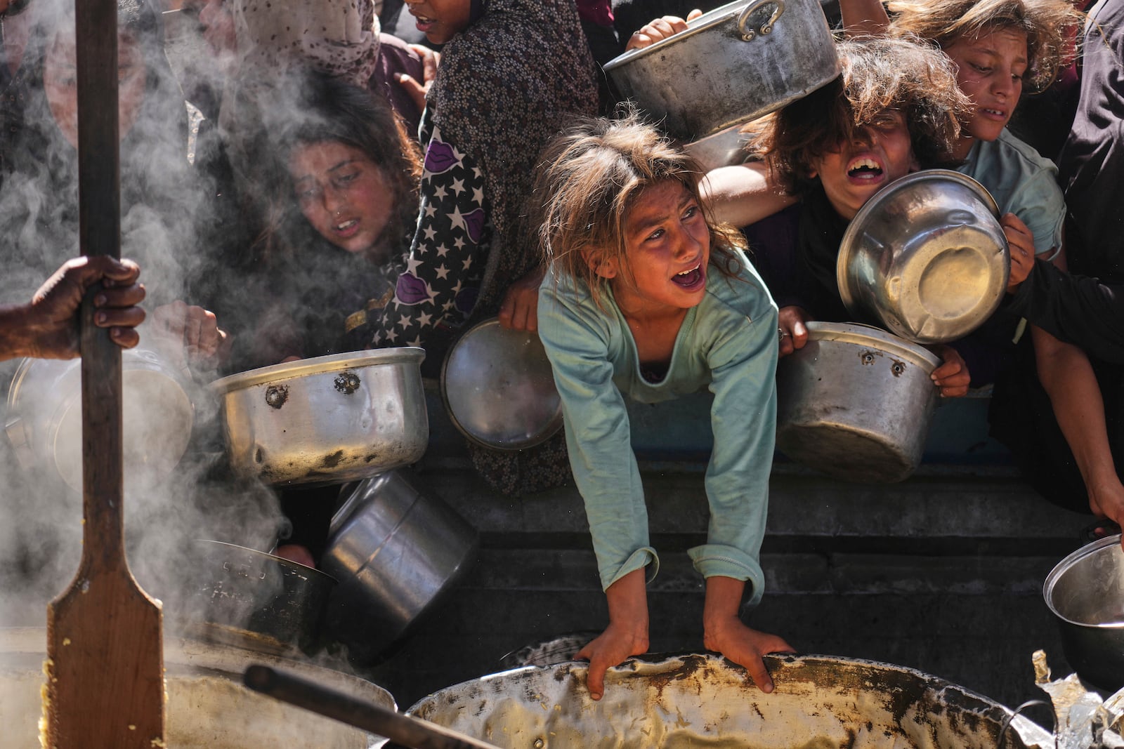 Palestinians struggle to get donated food at a community kitchen in Khan Younis, Gaza Strip, Friday, May 16, 2025. (AP Photo/Abdel Kareem Hana)