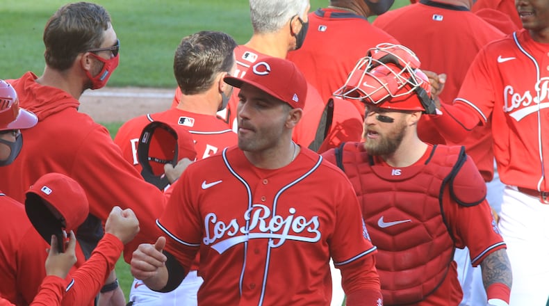 Joey Votto, center, and Tucker Barnhart, right, leave the field as the Reds celebrate a victory against the White Sox on Sunday, Sept. 20, 2020, at Great American Ball Park in Cincinnati. David Jablonski/Staff