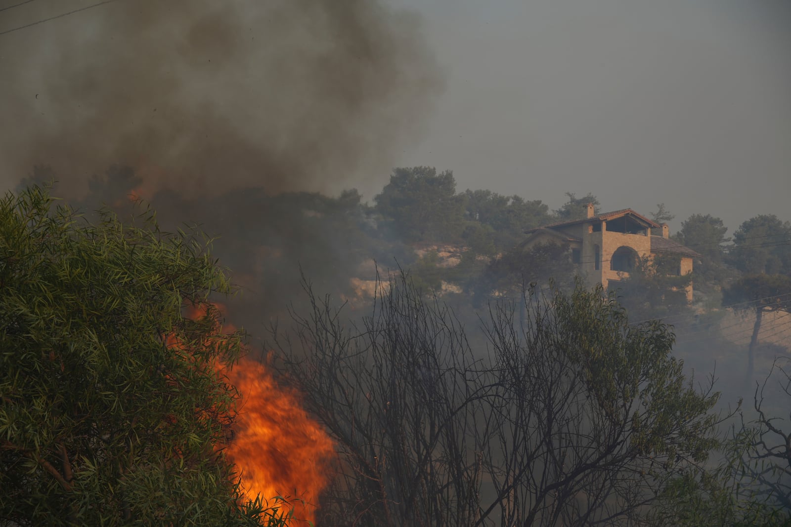 Flames burn near a house in Souni village, Cyprus, during a massive wildfire on the southern side of the east Mediterranean island nation's Troodos mountain range, Thursday, July 24, 2025. (AP Photo/Petros Karadjias)