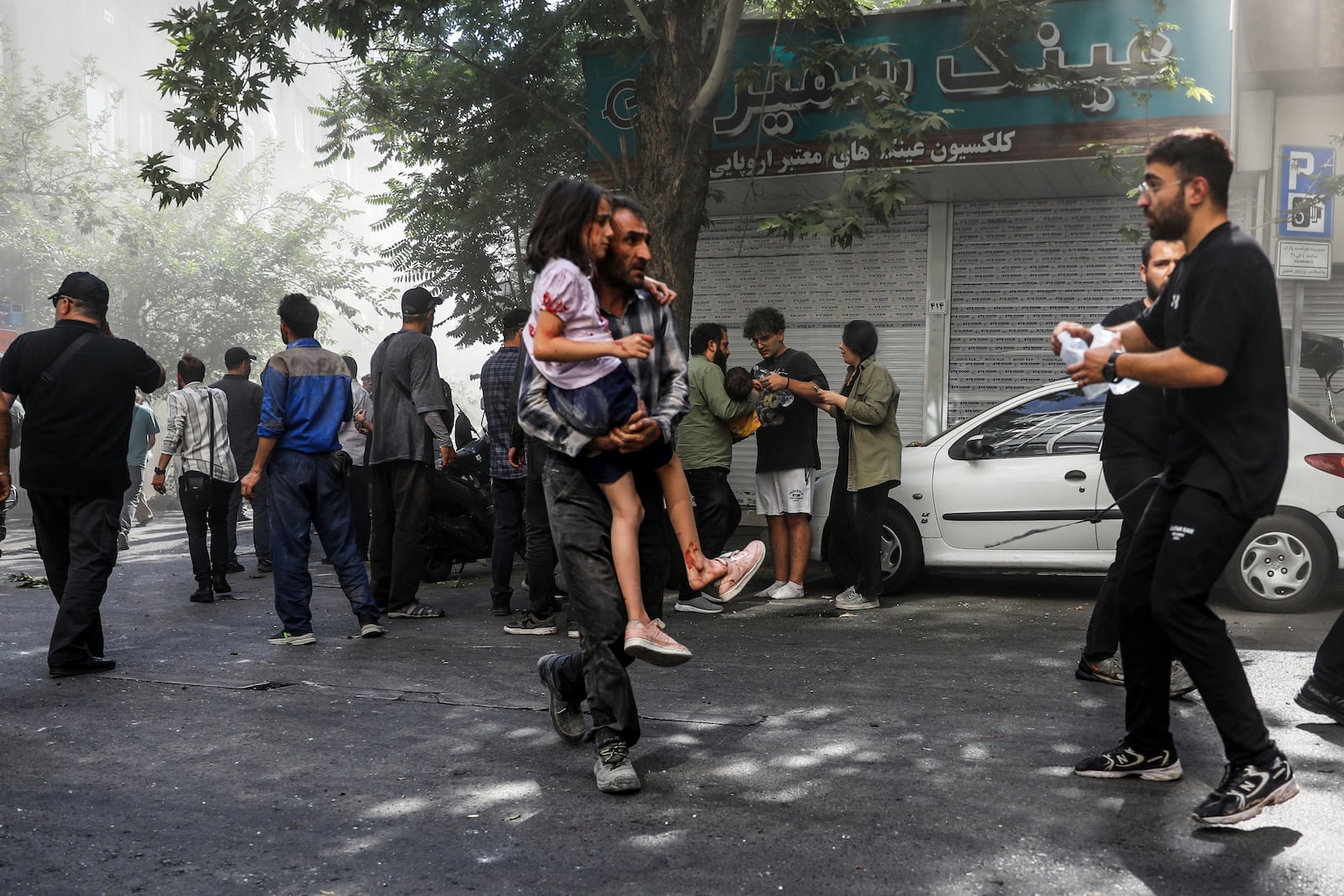 A man carries a wounded girl after an explosion in downtown Tehran amid Israel's two-day campaign of strikes against Iran, Sunday, June 15, 2025. (AP Photo/Morteza Zangene/ISNA)