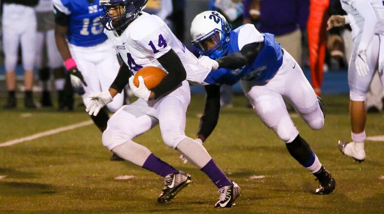 Middletown running back Alonso Corbin (14) is tackled by Hamilton linebacker Miquan Hubbard (28) during their game at Virgil Schwarm Stadium in Hamilton last weekend. GREG LYNCH/STAFF