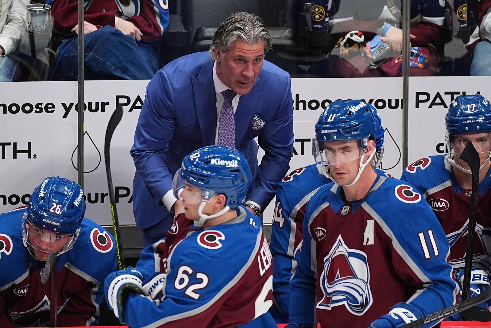 Colorado Avalanche head coach Jared Bednar, back, draws up a play for players during a time out in the third period of an NHL hockey game against the Vancouver Canucks Thursday, April 10, 2025, in Denver. (AP Photo/David Zalubowski)