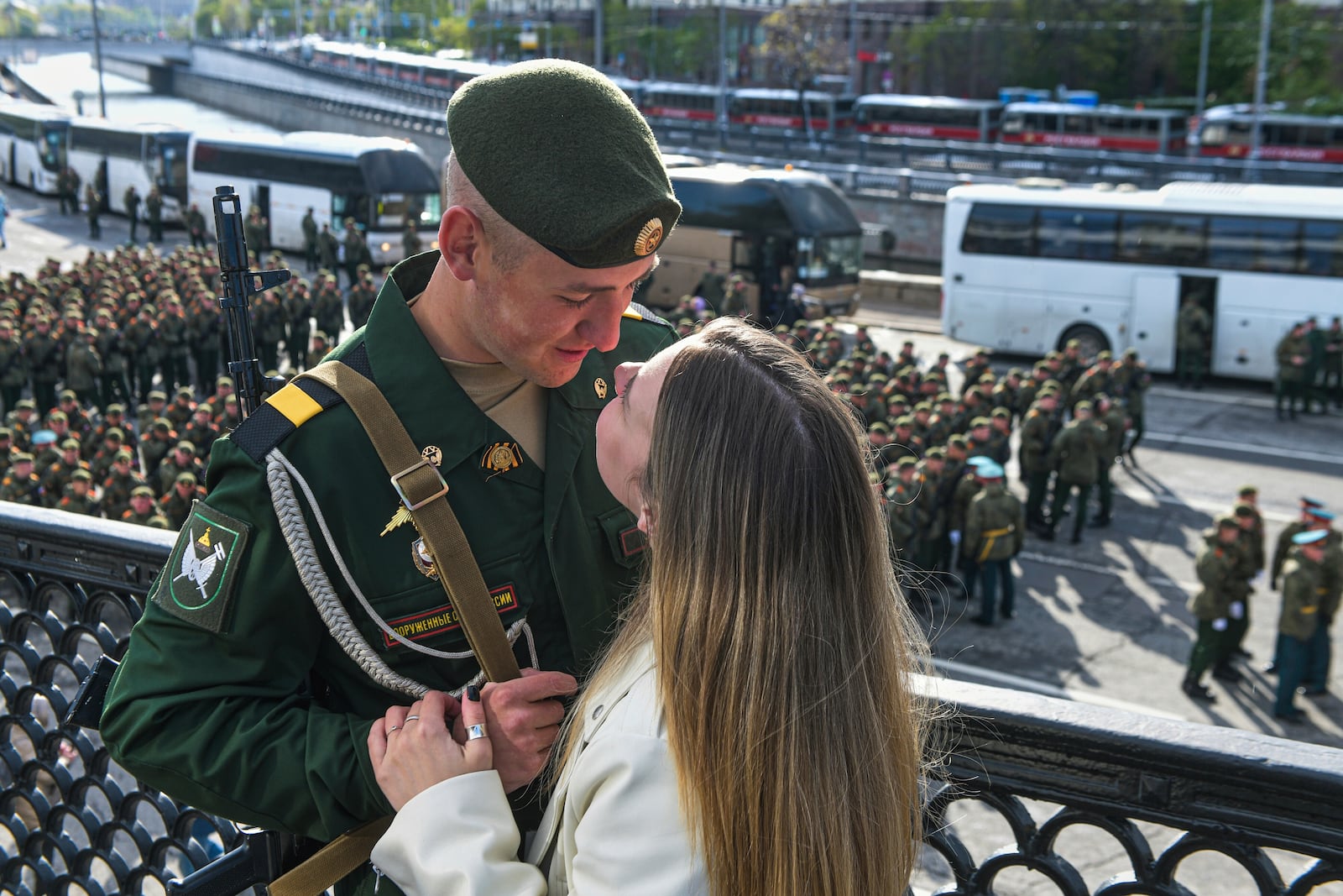 FILE - A Russian soldier and young woman share a tender moment as soldiers wait to attend the Victory Day military parade in Moscow on May 9, 2024. (AP Photo, File)