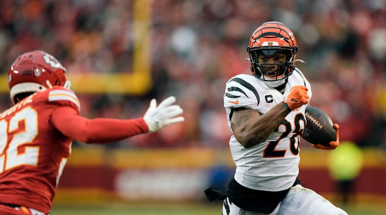 Cincinnati Bengals running back Joe Mixon (28) runs with the ball as Kansas City Chiefs cornerback Trent McDuffie (22) defends during the first half of an NFL football game Sunday, Dec. 31, 2023, in Kansas City, Mo. (AP Photo/Charlie Riedel)