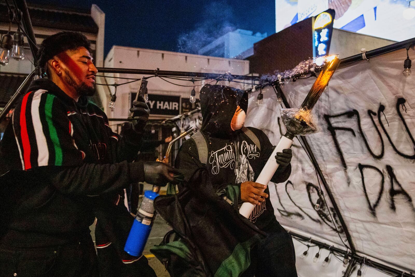 Protestors prepare to launch projectiles during protests over the Trump administration's immigration raids in Los Angeles, Monday, June 9, 2025. (AP Photo/Ethan Swope)