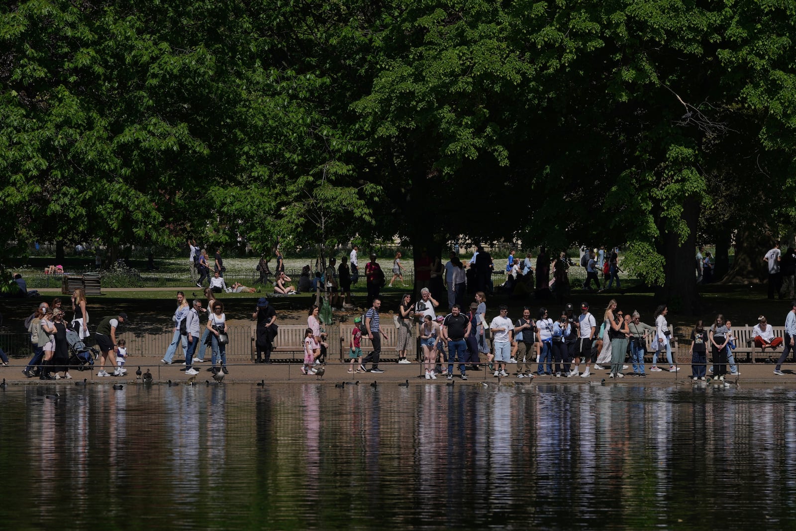 People walk on a sunny day at a park in London, Wednesday, April 30, 2025. (AP Photo/Kin Cheung)