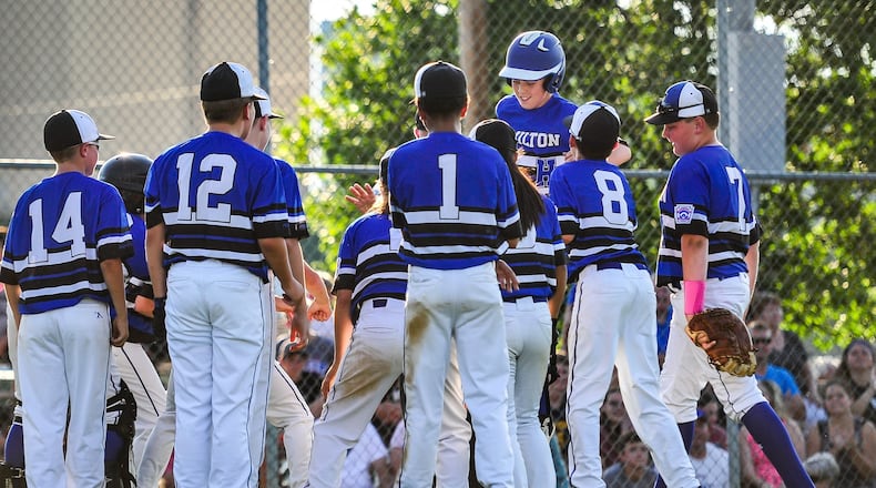 Hamilton West Side Little League’s Davis Avery is greeted by teammates at home plate after hitting one of his two home runs Monday night at West Side. The Hamilton squad beat Lebanon 10-0 to capture the District 9 tournament championship. NICK GRAHAM/STAFF