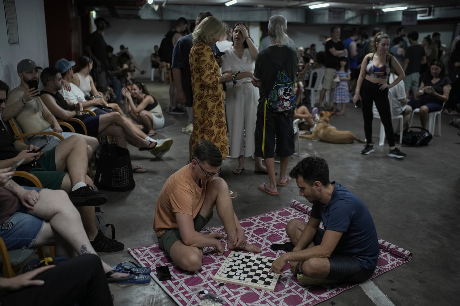 People take shelter as air raid sirens warn of incoming Iranian strikes in Tel Aviv, Israel, Friday, June 20, 2025. (AP Photo/Leo Correa)