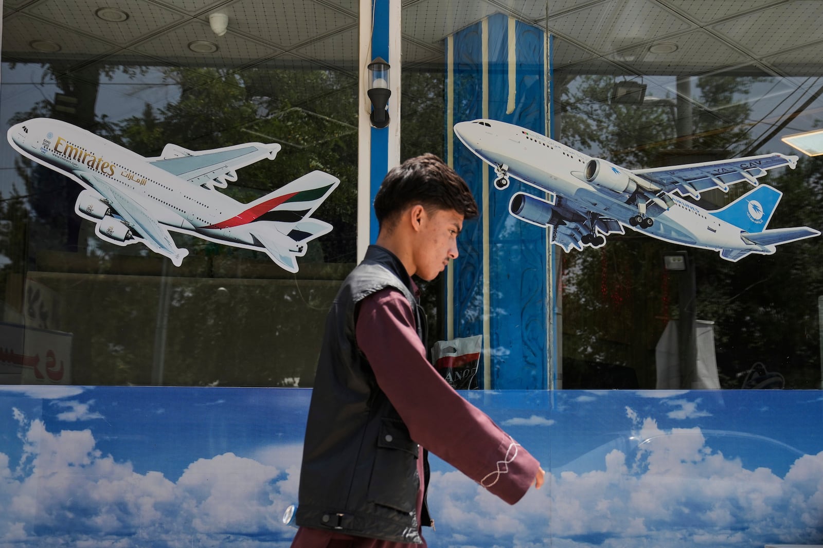 An Afghan man passes in front of an air travel agency in Kabul, Afghanistan, Thursday, June 5, 2025. (AP Photo/Ebrahim Noroozi)