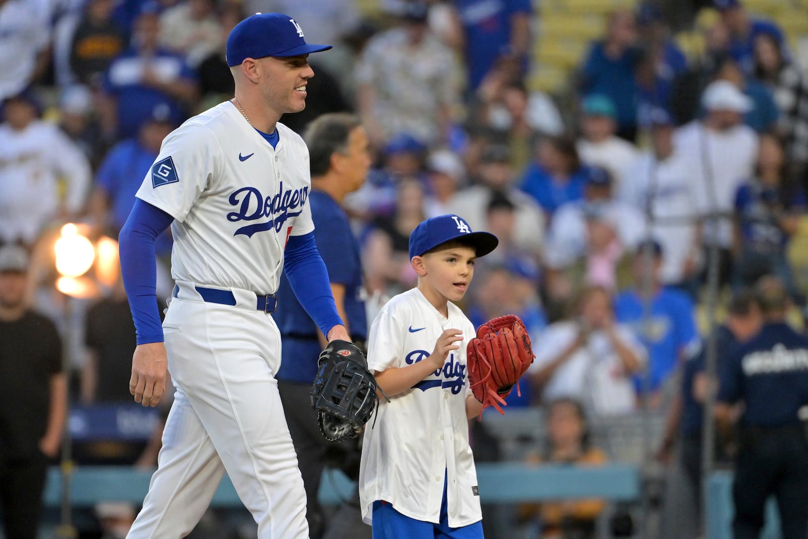 Los Angeles Dodgers first baseman Freddie Freeman walks with his 9-year-old son Charlie after he threw out the first pitch before a baseball game against the Chicago Cubs, Friday, April 11, 2025, in Los Angeles. (AP Photo/Jayne Kamin-Oncea)