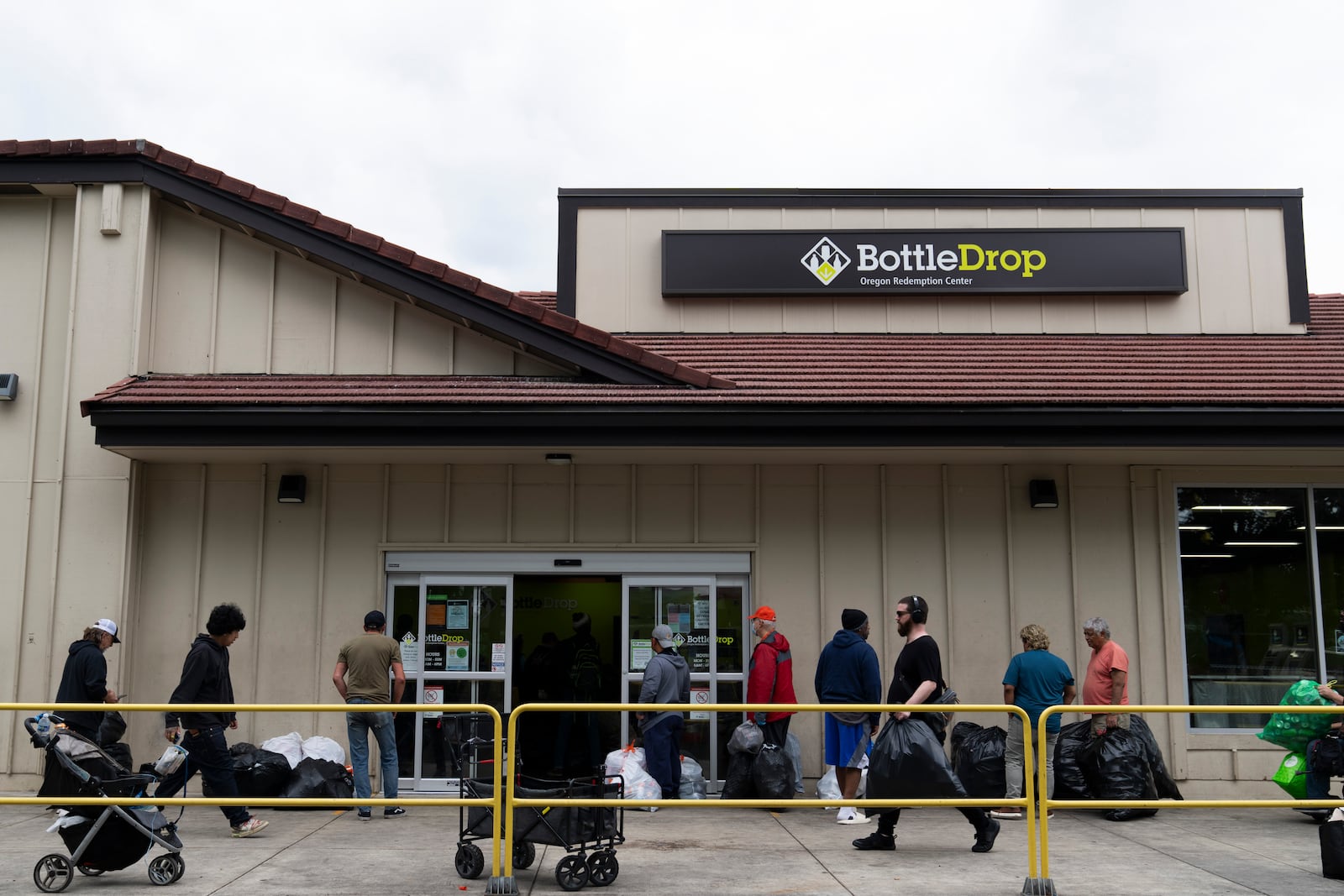 People wait in line outside the Glisan BottleDrop Redemption Center on Thursday, May 15, 2025, in Portland, Ore. (AP Photo/Jenny Kane)
