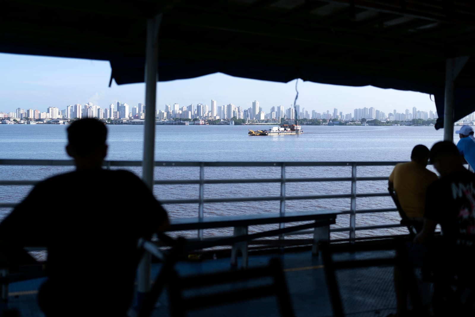 FILE - People look out at the coast of Belem, Brazil, as a boat nears shore, March 23, 2025. (AP Photo/Jorge Saenz, File)