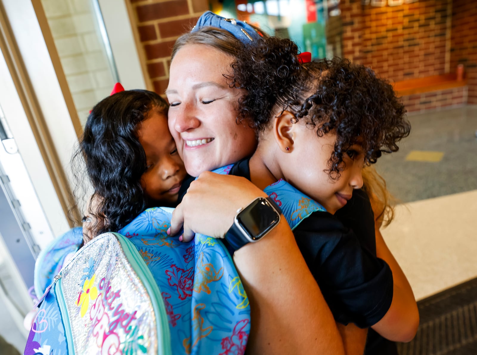 Kindergarten teacher Katie Chadwick hugs former students, Nyomi Printup, left, and Nyla Printup, 6, on their first day of first grade Tuesday, Aug. 12, 2025 at Brookwood Elementary School in Hamilton. NICK GRAHAM/STAFF