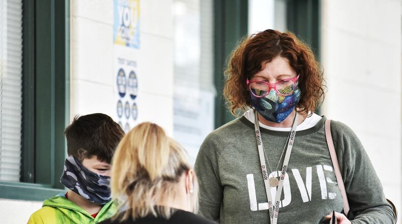 Amy Powell stands with her son, Murphy, 9, as she and other school faculty lined up for Covid-19 vaccines administered by Kroger Wednesday, February 3, 2021 at Lakota West High School in West Chester Township. NICK GRAHAM / STAFF